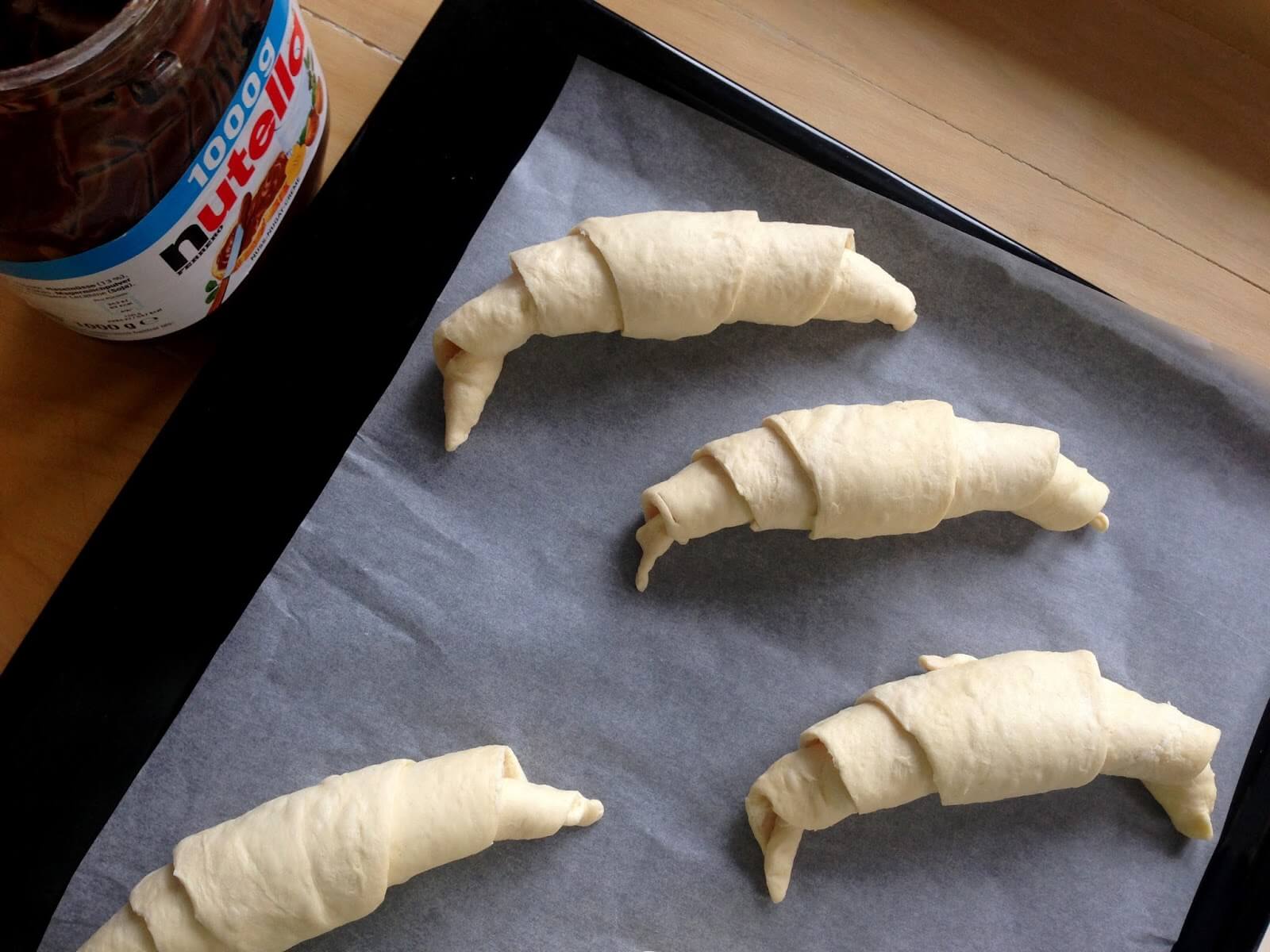 A croissantokat rakjuk rá egy sütőpapírra. Még nőni fognak, ezért rakjuk őket egy kicsit távolabb egymástól. 